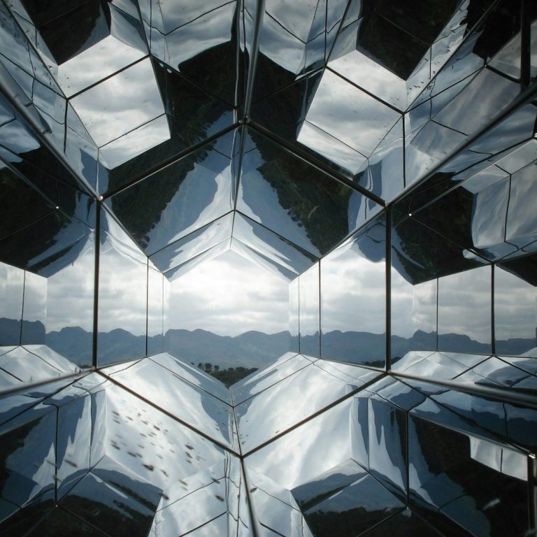 Geometric reflections create a kaleidoscopic view of mountains and sky.